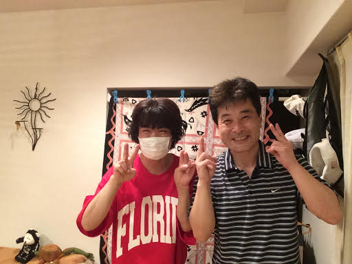赤いスウェットを着た男性のお客様と前田歩の笑顔のツーショット写真