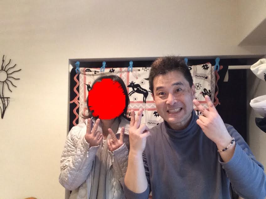 写真加工で顔を隠し白いダウンジャケットを着た女性のお客様と前田歩の笑顔のツーショット