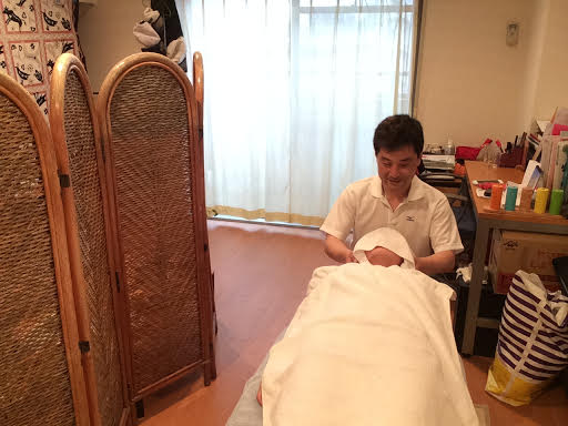 前田歩が仰向けの女性のお客様へ首へ整体マッサージの施術をしているところ