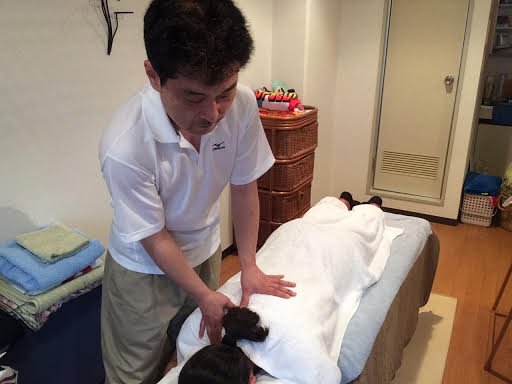 前田歩がうつ伏せの女性のお客様へ右肩への整体マッサージ施術をしているところ